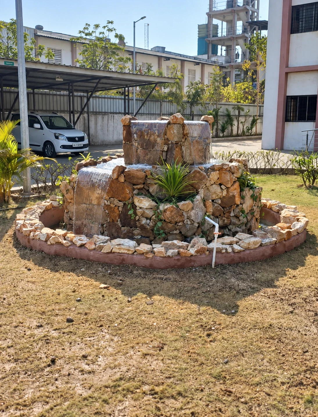 A tiered stone water feature and planting in a campus courtyard.